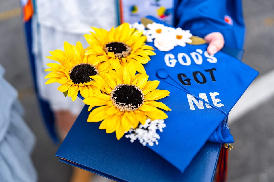 Blue graduation cap decorated with sunflowers and the words "God's Got Me"