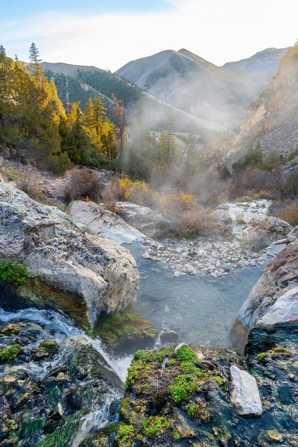 Steaming natural hot spring pools among rocks in a mountain canyon