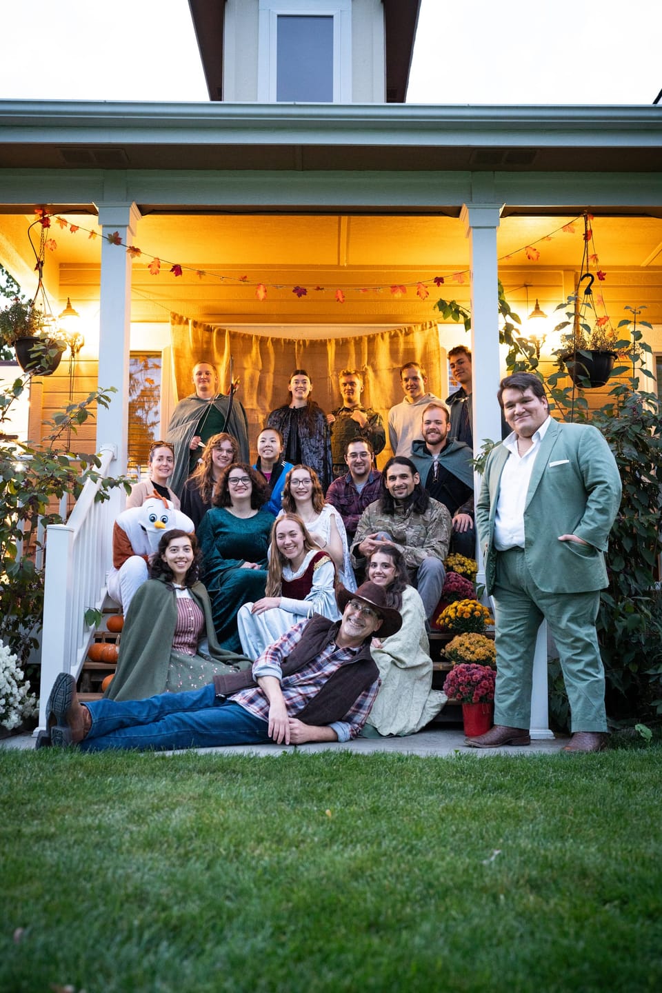 Large family group posed on and around a warmly lit porch decorated for autumn