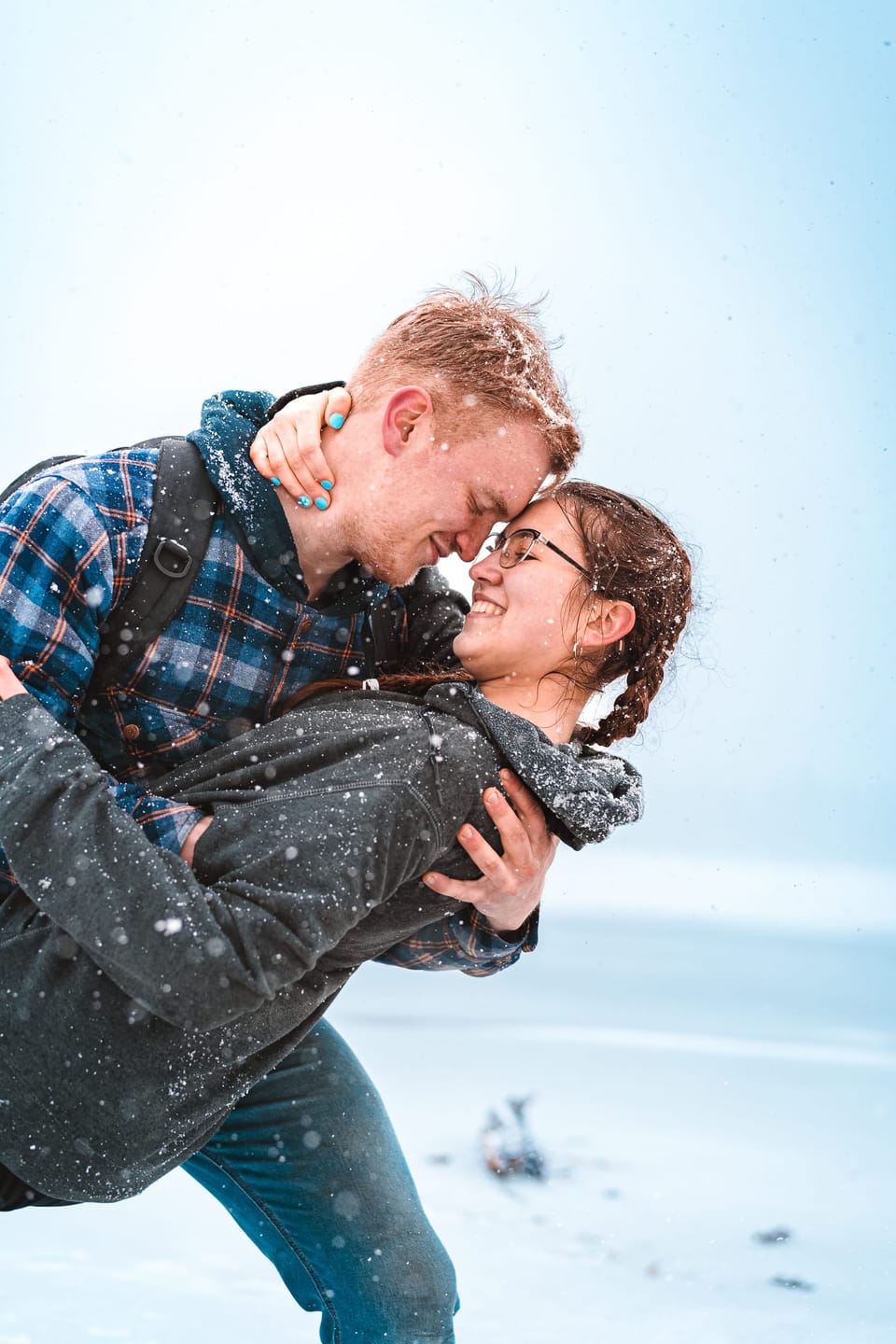 Man dipping a laughing woman during a snowy outdoor couples session