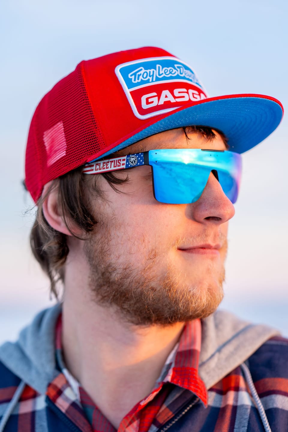 Young man in a red cap and blue mirrored sunglasses against a blue sky