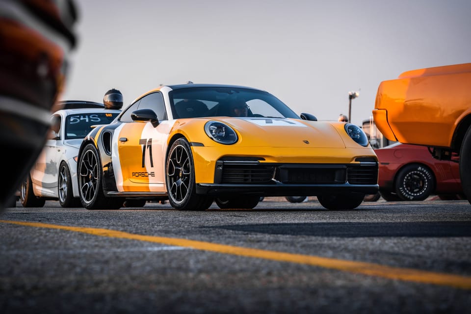 Yellow Porsche 911 with racing number 71 at an outdoor car meet, shot from a low angle