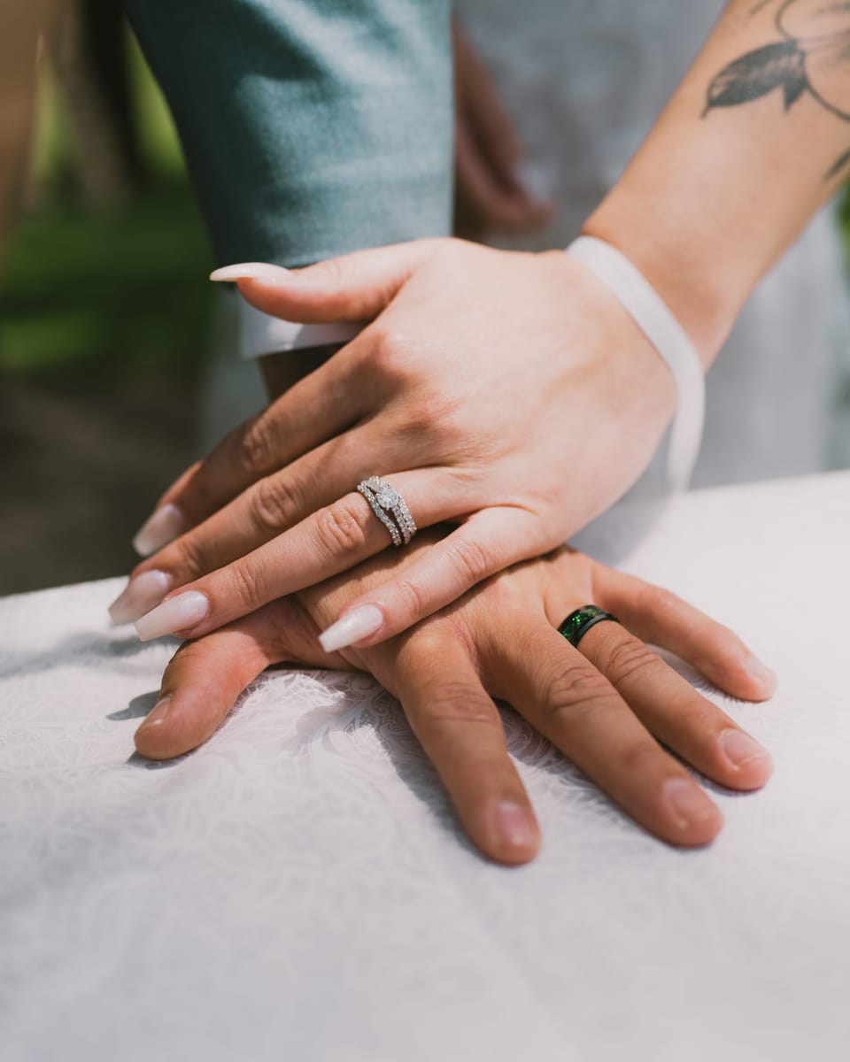 Close-up of a couple's hands showing an engagement ring and a wedding band